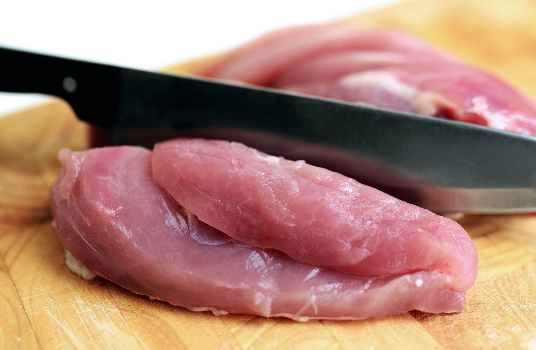 Raw chicken meat being sliced